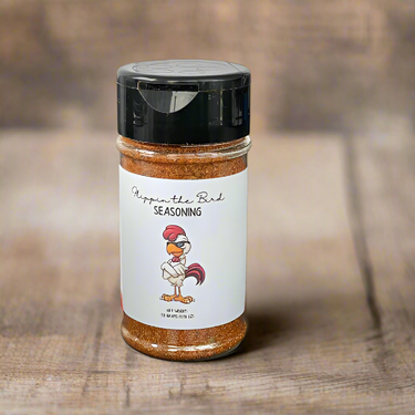 A jar of Flippin the Bird 🐔 Salt-Free Grilling & Roasting Blend, featuring a cartoon chicken with glasses on the label, sits on a wooden surface.